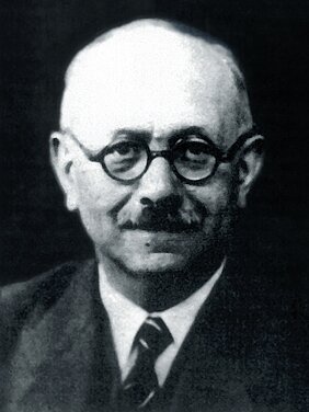 Schwarz-weiß Portrait von Marc-Bloch, er trägt Anzug, ein weißes Hemd, eine Kravatte, Brille und einen Schnauzbart